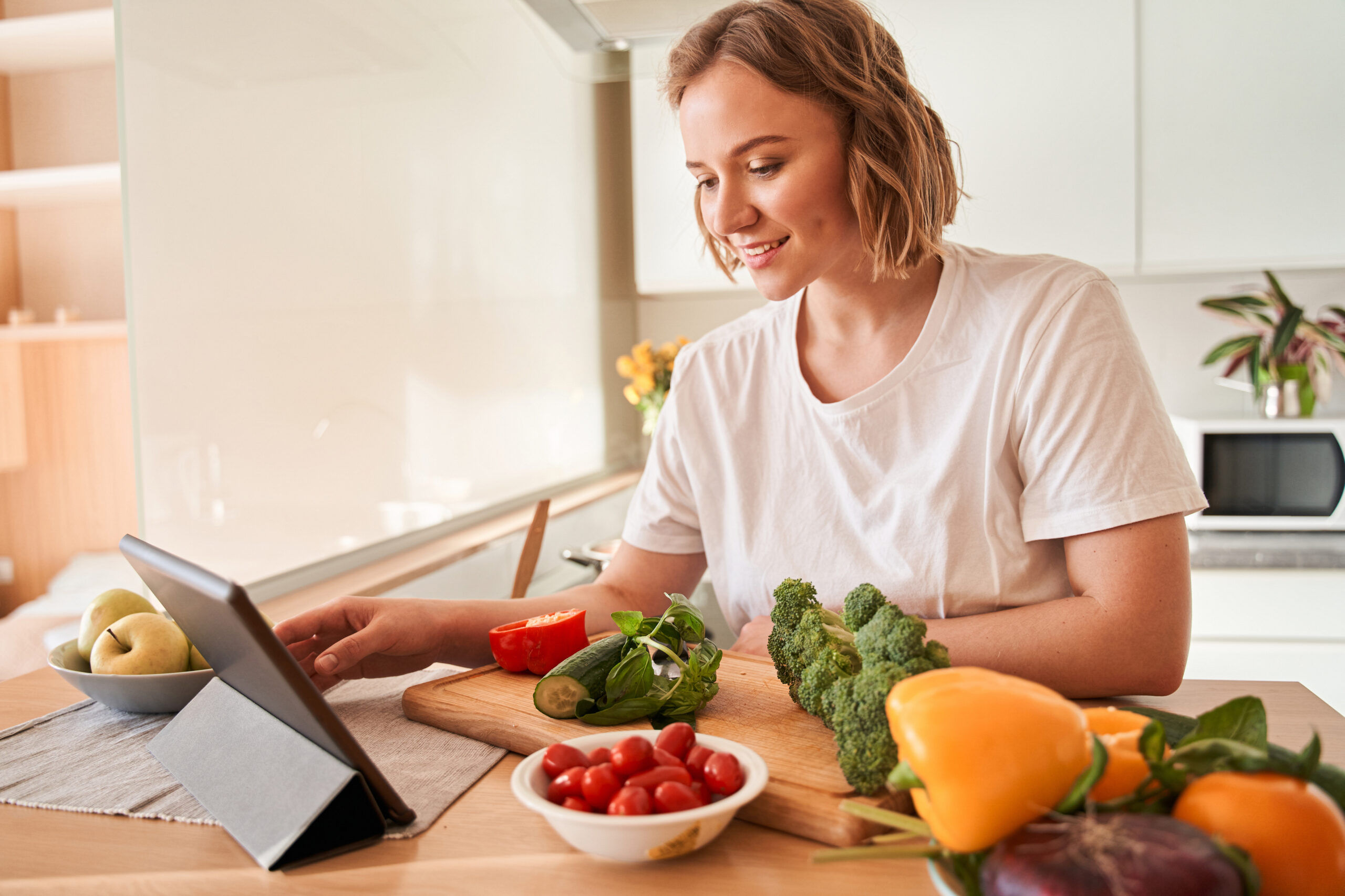 Woman looking at IFM's food plan while cooking, which helps her support biotransformation and liver detoxification.