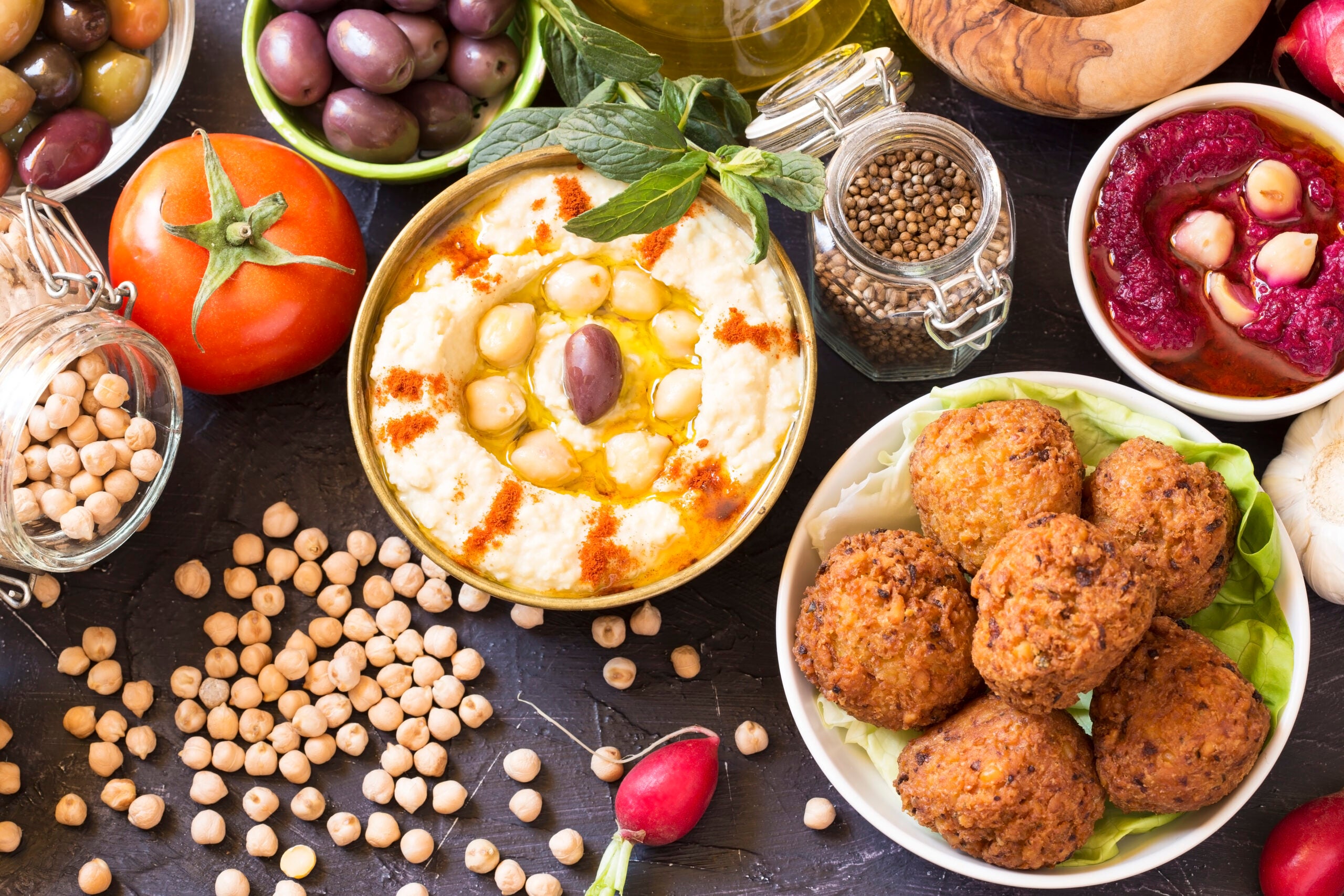 A flat lay of anit-inflammatory mediterranean foods, hummus, beans, olives, falafels, that may help repair gut permeability and decrease non-celiac gluten sensitivity (NCGS).