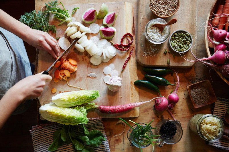 Woman chopping carrots while cooking dinner. Woman is making fermented vegetables / Sauerkraut. Overhead.